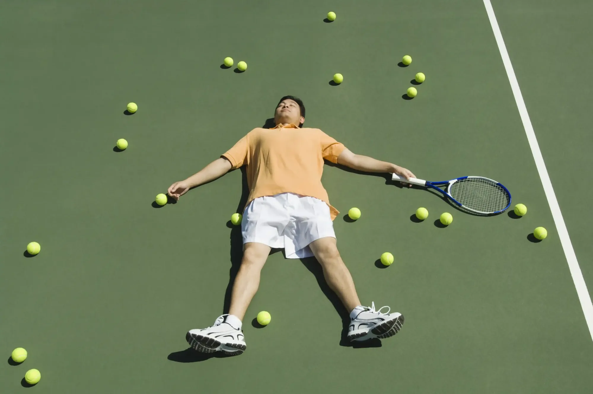tennis-player-lying-down-among-balls-1918275